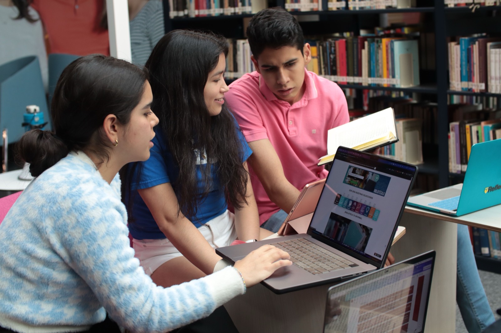 Students studying together with laptops and books in a library